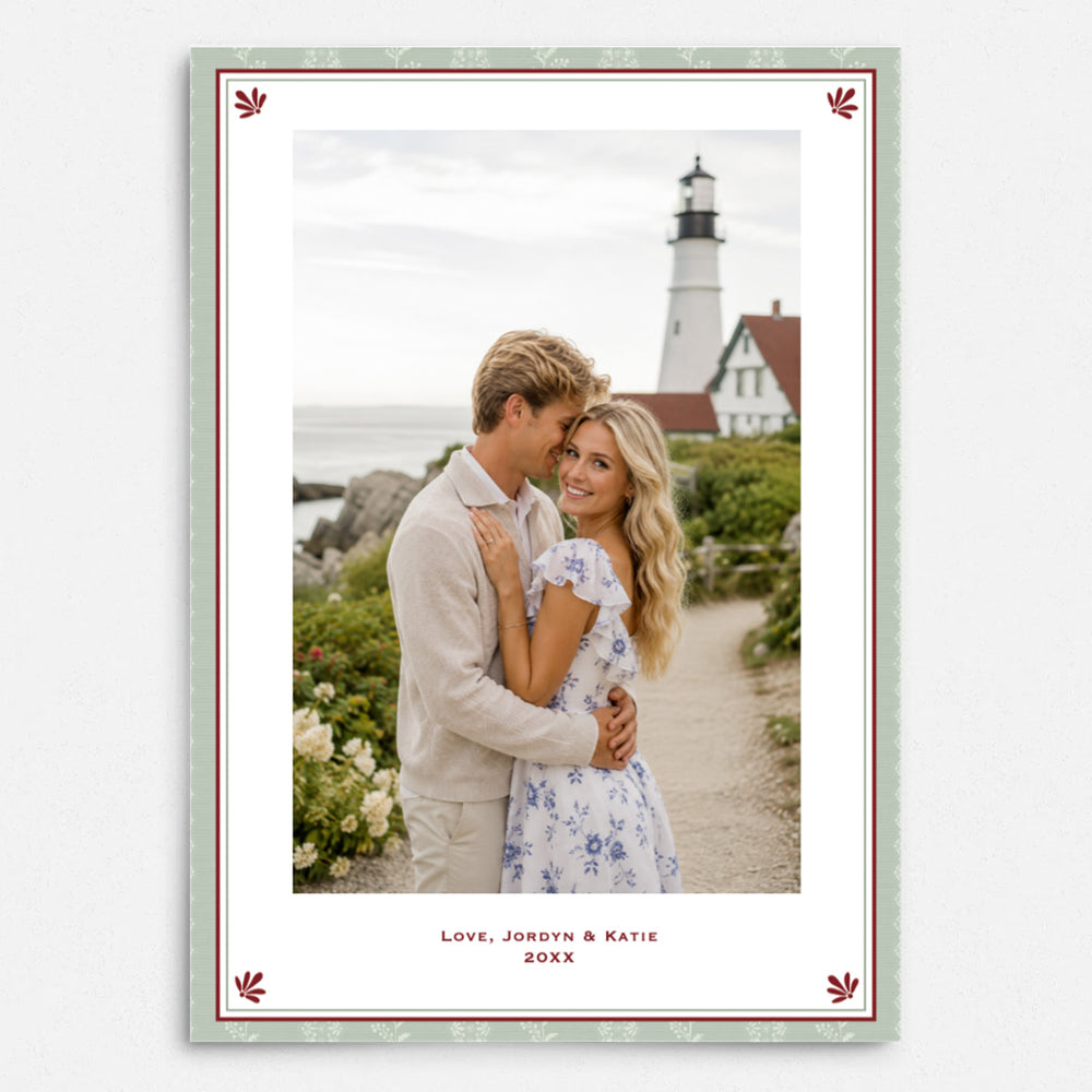 A personalized photo print with a decorative border, featuring a couple embracing in front of a lighthouse. The print has a white center, a red inner border, a pale green outer border, and custom text at the bottom reading 'Love, Jordyn & Katie 20XX'.